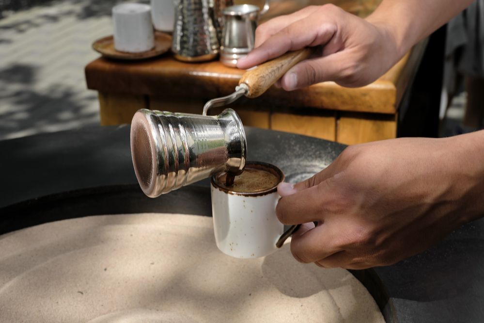 barista-pours-freshly-made-turkish-coffee-into-cup-closeup-professional-barista-prepares-coffee-by-hand-traditional-way-sand-selective-focus-space-text.jpg
